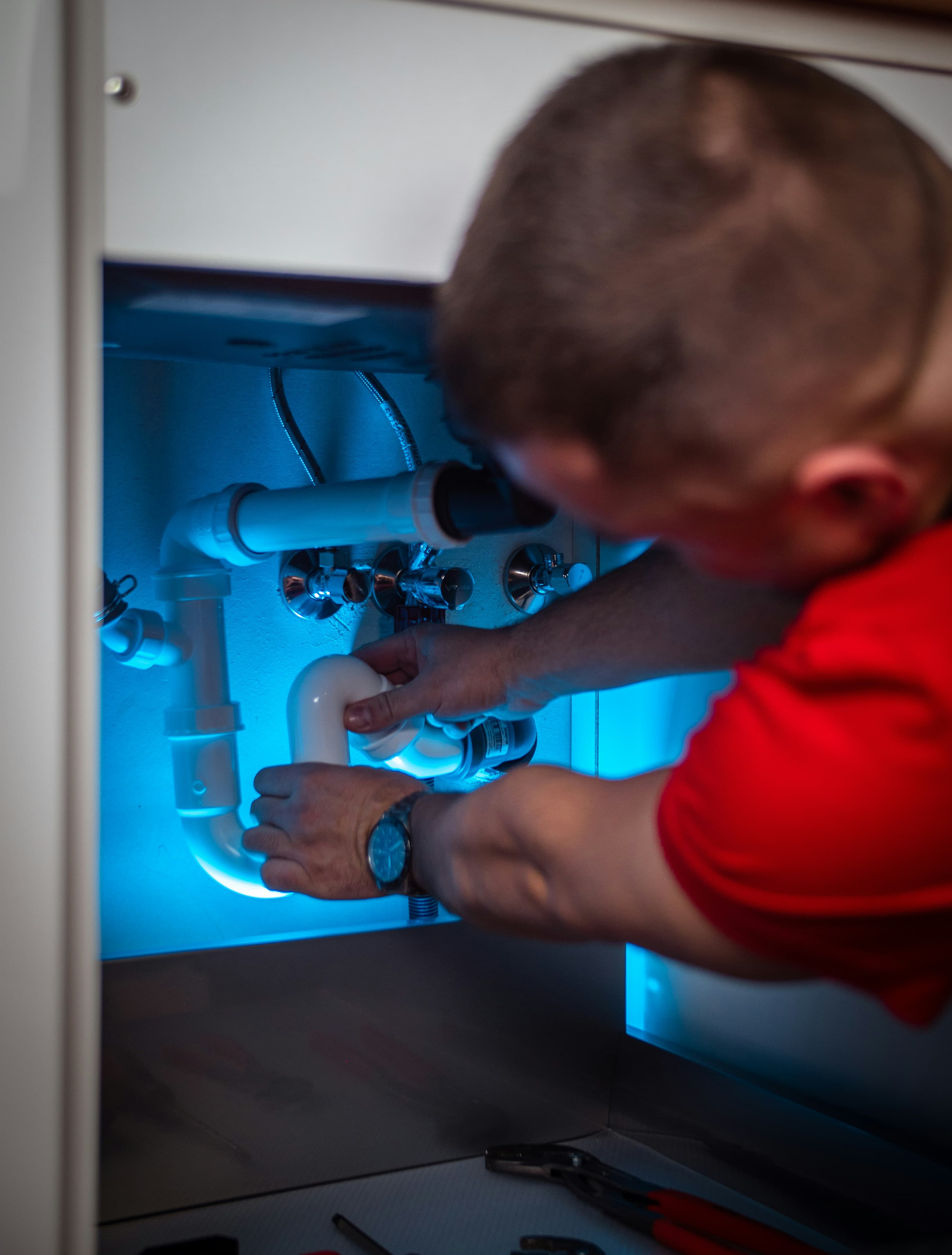 A plumber fitting pipes under a sink