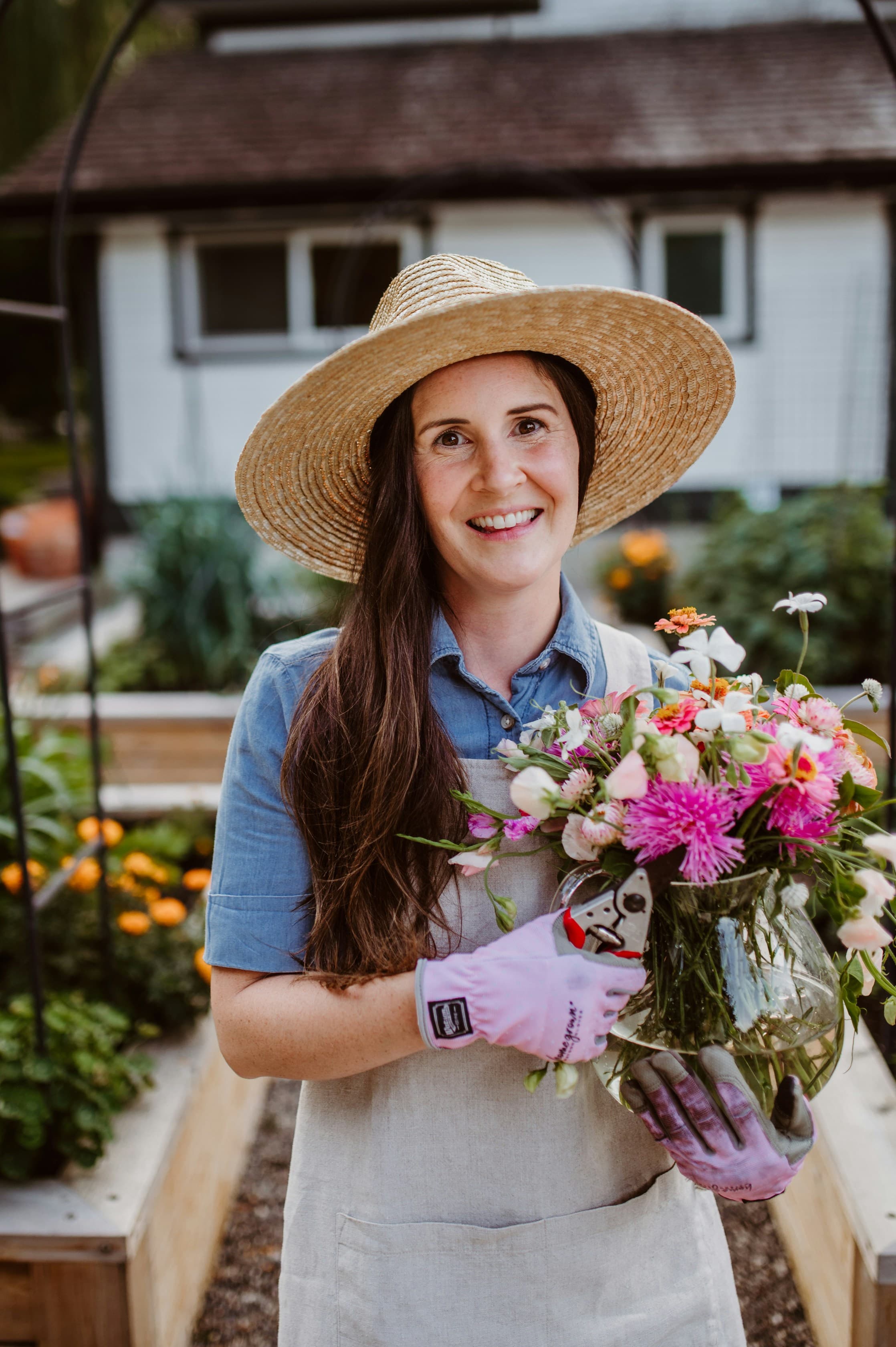 A smiling florist holding a bouquet outside her flower shop
